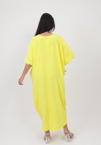 Żółty, luźny kaftan z krótkimi rękawami i teksturowanym materiałem. Posiada okrągły dekolt i sięga do połowy łydki. Przejrzysty, minimalistyczny design.