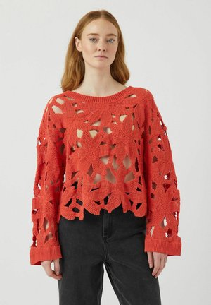Maglione lavorato a maglia corallo con motivo floreale aperto, maniche lunghe e polsini a costine. Progettato con una silhouette cropped e una finitura texturizzata.
