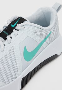 Pantofii sport Nike în mesh gri deschis cu un logo turcoaz, accente texturate și un etichetă neagră. Prezintă o talpă din cauciuc durabilă.