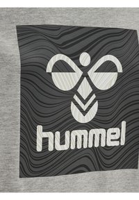 Grått tyg med ett svart mönster av vågiga linjer och en vit logo av en stiliserad figur samt ordet "hummel" i modern font.
