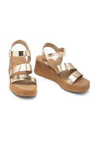 Metaliczne złote sandały na koturnie z trzema poziomymi paskami, zapięcie na klamrę oraz teksturowanym obcasem z korka. Gładka wewnętrzna podeszwa i wyściółka amortyzująca.