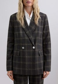 Blazer de cuadros de doble botonadura en marr�ón oscuro y gris, con botones plateados, dos bolsillos frontales y una tela suave y texturizada.