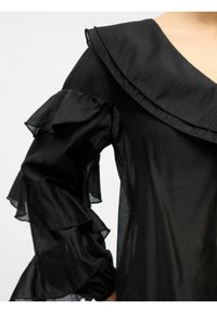 Zwarte blouse met een diepe V-hals en grote geplooide kraag. Lange mouwen met geplooide accenten bij de manchetten. Lichtgewicht, doorschijnende stof.