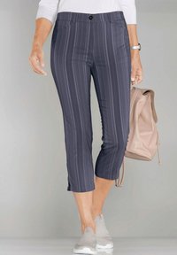 Grijs gestreepte cropped broek met een knoopsluiting, twee voorkuilen en een gladde textuur, gecombineerd met lichte sneakers en een beige rugzak.