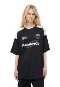 Maglia sportiva nera con maniche corte, dettagli bianchi sulle spalle, che presenta il logo "ADVANCE" e altri emblemi. Realizzata in tessuto testurizzato.