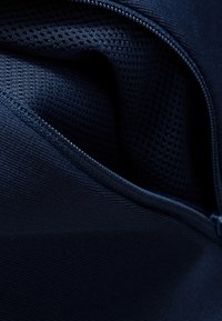 Mörkblå dragkedjesydd tyg med en texturerad meshinteriör. Slät utsida med ribbad yta och kontrasterande söm längs kanterna.