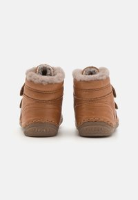 Hnědé kožené kotníkové boty s měkkou šedou kožešinovou podšívkou, dvojicí suchých zipů a zaoblenou špičkou. Prošití podél podrážky.