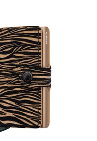 Billetera a rayas zebra en negro y marrón, hecha de ante texturizado, con cierre de botón y un acento metálico con la marca "SECRID".