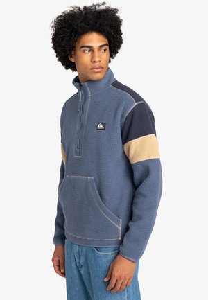 Fleece pullover in blauw met marineblauwe en beige accenten. Voorzien van een halve rits, een voorzak en een textuurafwerking.