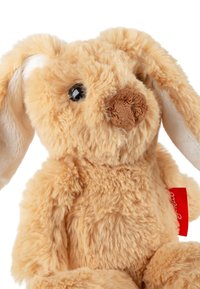 Soft beige plush rabbit with long floppy ears, a brown nose, and black eyes. Features a red tag attached to the side.