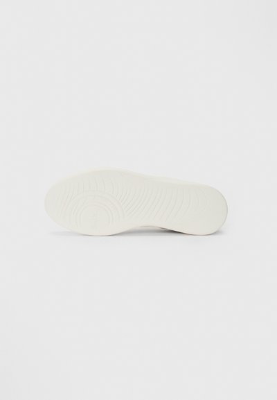 Suola di sneaker bianca con un motivo testurizzato, caratterizzata da un logo sottile e un bordo liscio. Progettata per comfort e stabilità.