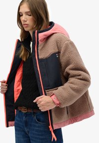 Veste en polaire avec un corps marron et des manches bleu marine, dotée d'une capuche rose et d'accents. Fermeture éclair et poches pour les mains mentionnées.
