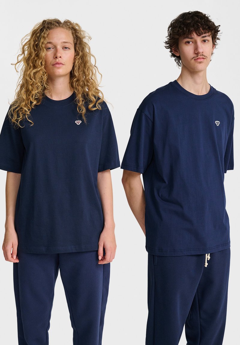 Marinblå bomulls t-shirts med korta ärmar, med en liten broderad design på bröstet, i kombination med matchande marinblå byxor.