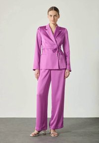 Satenast komplet v barvi fuksije, ki vključuje blazer z ovratnikom z zarezo in hlače s pravimi nogami. Gladek zaključek in eleganten dizajn.