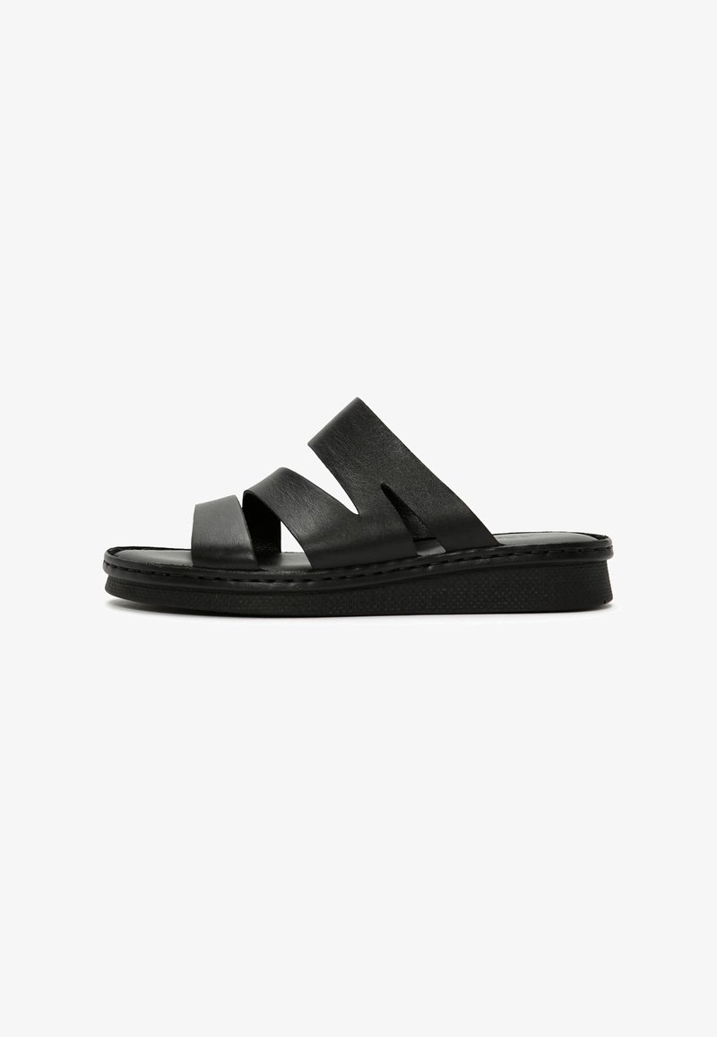 Zwarte slidesandalen met drie brede banden, een gestructureerd oppervlak en een lage platformzool met zichtbare stikdetails.