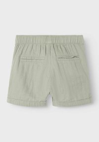 Ljusgröna shorts med texturerad tyg, elastisk midja och två bakfickor, samt uppvikta fållar vid bensluten.
