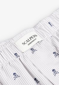 Tissu rayé gris avec un motif de petits cr�ânes et os croisés navy ; présente une étiquette en tissu blanc avec "SCALPERS UNDERWEAR" imprimé.