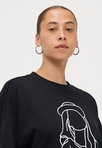 Sweatshirt preto com mangas longas, apresentando um design de linha branca na parte da frente. Feito de um tecido suave com um decote clássico.