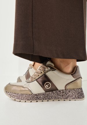Beige and brown sneakers featuring a textured upper, metallic accents, and a speckled platform sole. Laces and logo detail visible.
