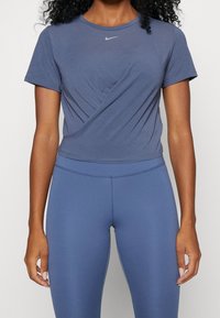 Navy blue Nike T-shirt with a slim fit and short sleeves, featuring a rounded neckline and a subtle twisted design at the front.