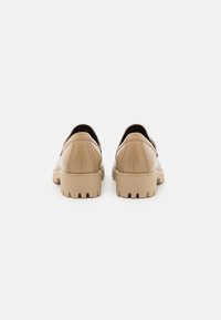 Chaussures en cuir beige avec un bout arrondi, un petit talon et une semelle texturée comportant des rainures. Fini lisse avec des détails de couture subtils.