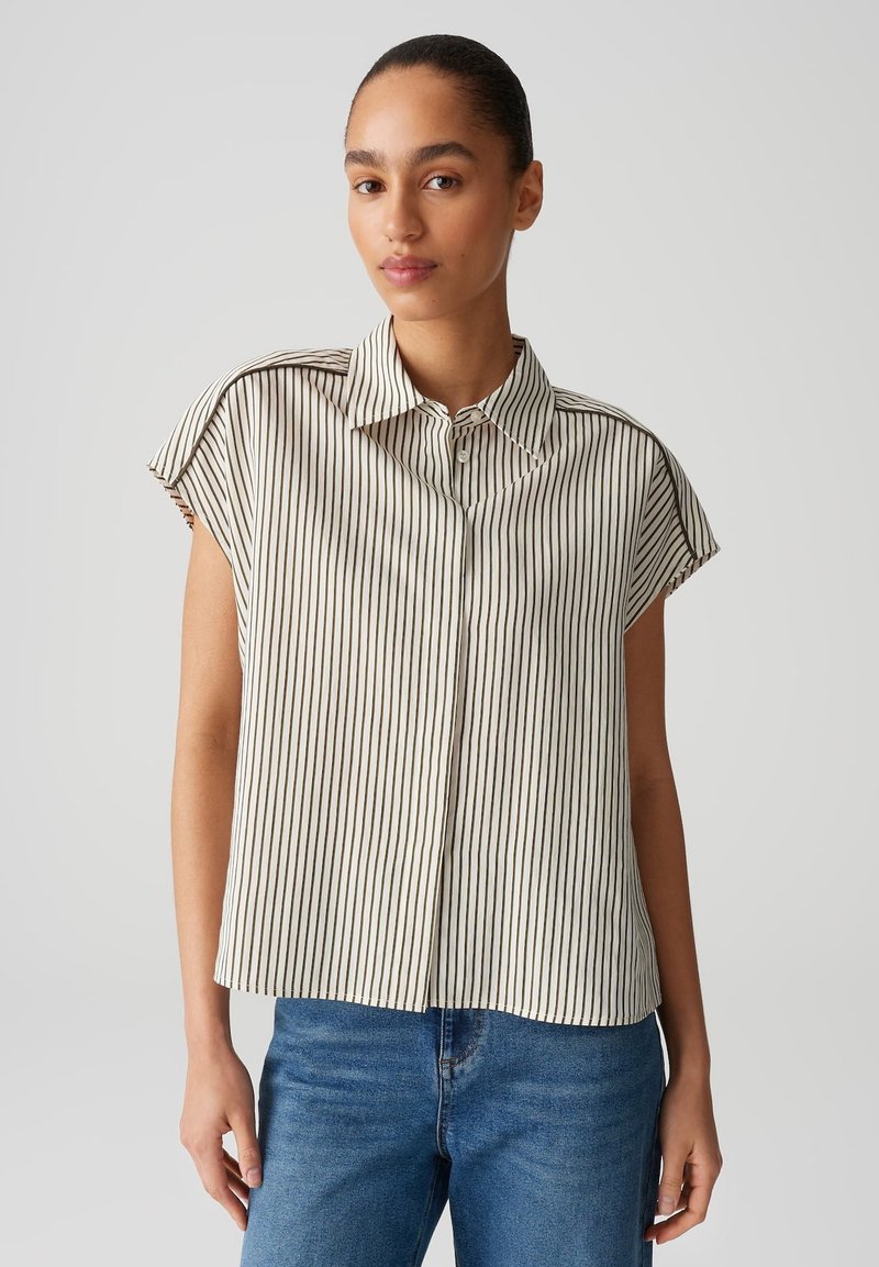 Blusa leggera a righe in beige e marrone scuro, con colletto, maniche corte e chiusura frontale con bottoni.