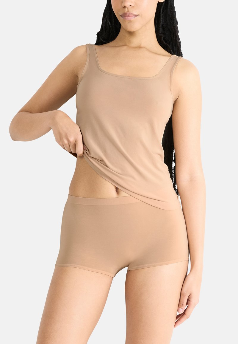 Nude naadloze tanktop en boyshorts, gemaakt van zachte, rekbare stof, met een fitted ontwerp en een gladde textuur.