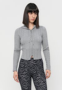 Gray zip-up hoodie with ribbed-knit texture and cable knit details, paired with black zebra-print leggings.