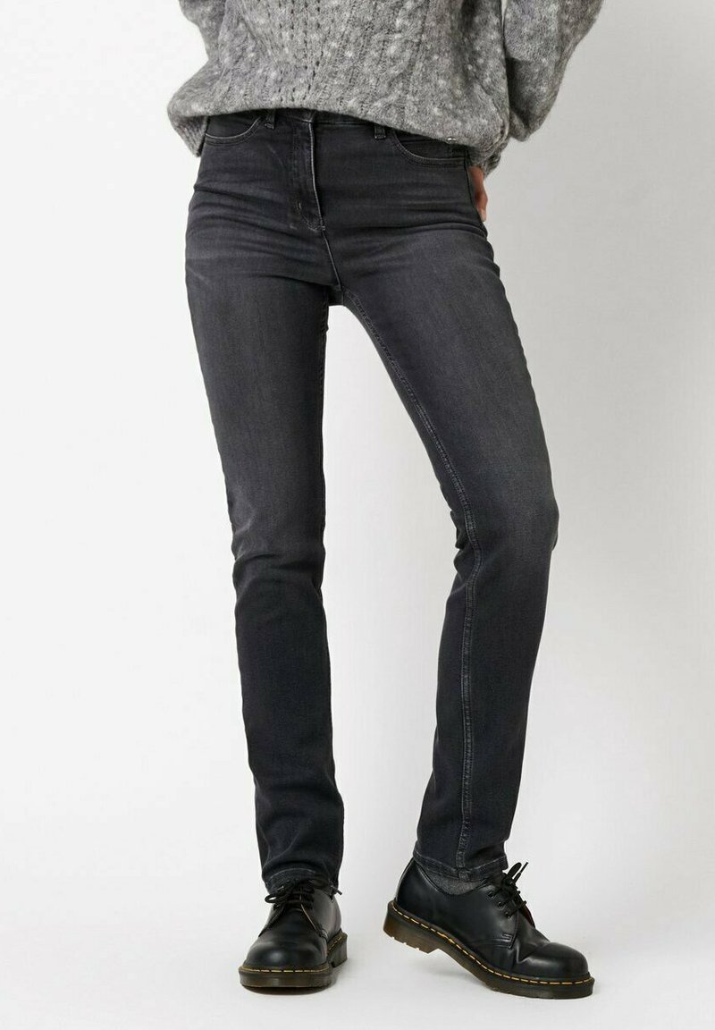 Schwarze Slim-Fit-Jeans aus Denim mit klassischem 5-Taschen-Design und dezentem Used-Look vorne, kombiniert mit schwarzen Schnürstiefeln.