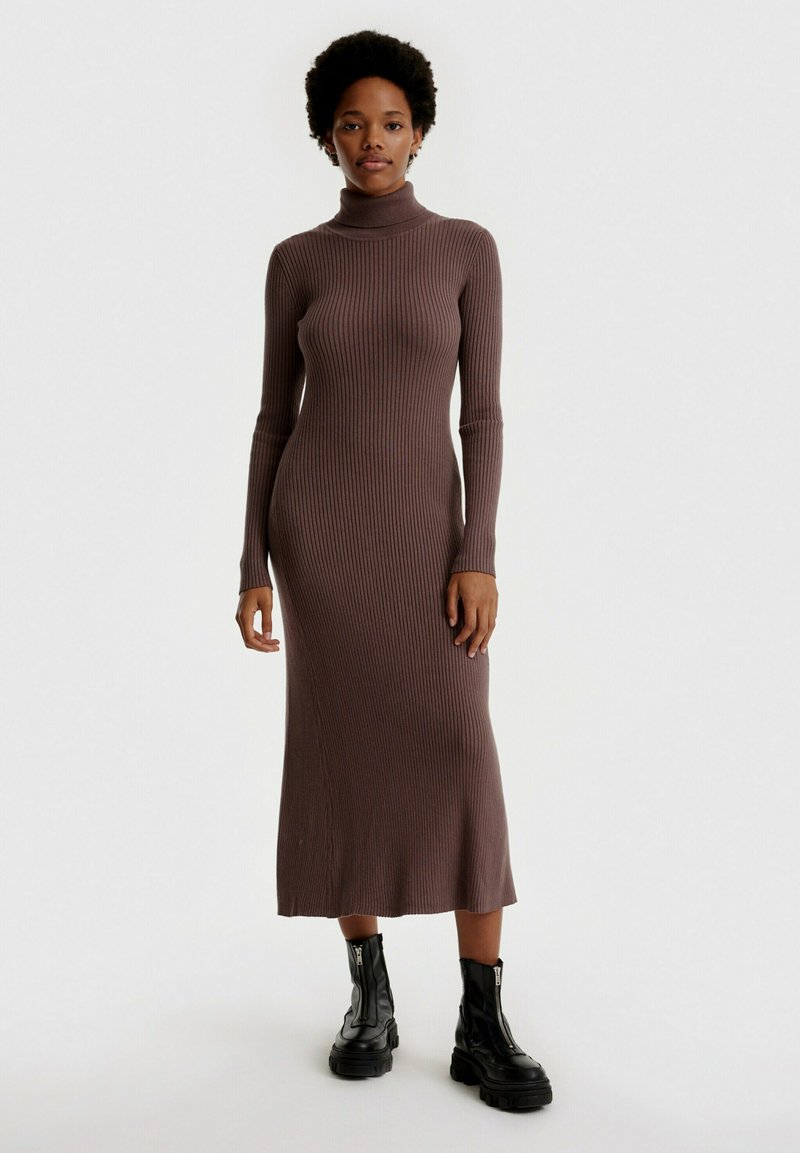 Rippstrick-Turtleneck-Midikleid aus braunem Stoff, mit langen Ärmeln und taillierter Silhouette, kombiniert mit schwarzen Combat Boots.