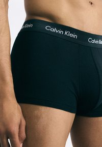 Boxeri din bumbac negri, cu un design ajustat, având o textură netedă și o bandă elastică cu marcă, de culoare gri închis, cu litere albe.