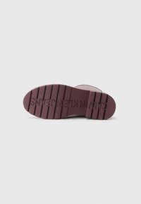 Semelle de chaussure en caoutchouc bordeaux avec des rainures texturées, portant l'inscription "CALVIN KLEIN JEANS" en relief, design plat pour plus de stabilité.