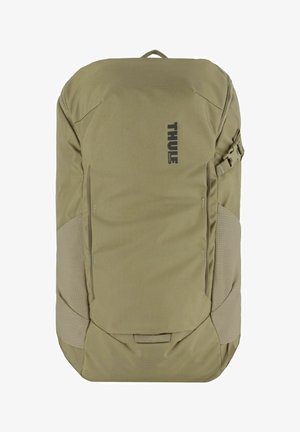 Zaino Thule in tessuto beige con un motivo testurizzato, dotato di un logo centrale, tracolla regolabile e tasche laterali per la conservazione.