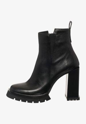 Bottine en cuir noir avec un bout carré et un talon bloc épais. Dotée d'une fermeture éclair latérale et d'une semelle en caoutchouc texturée pour une meilleure adhérence.