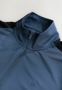 Niebieska sportowa kurtka z wysokim kołnierzem, zapięciem na pół suwaka i czarnymi akcentami na rękawach; gładka tkanina o subtelnym połysku.