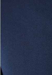 Nahaufnahme eines dunkelblauen gestrickten Stoffes mit engen, gleichmäßigen Stichen, die die Struktur des Gewebes detailliert zeigen.