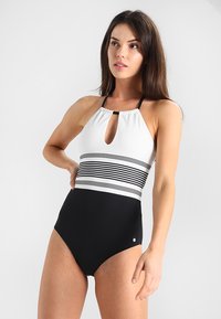 Monokini noir et blanc avec un col halter, comportant une découpe en forme de trou de serrure et des rayures horizontales sur le torse. Texture lisse.