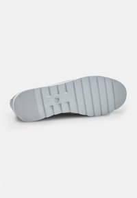 Suola di sneaker bianca in gomma con un motivo di grip testurizzato e scanalature orizzontali, caratterizzata da un'impronta circolare del logo vicino al centro.