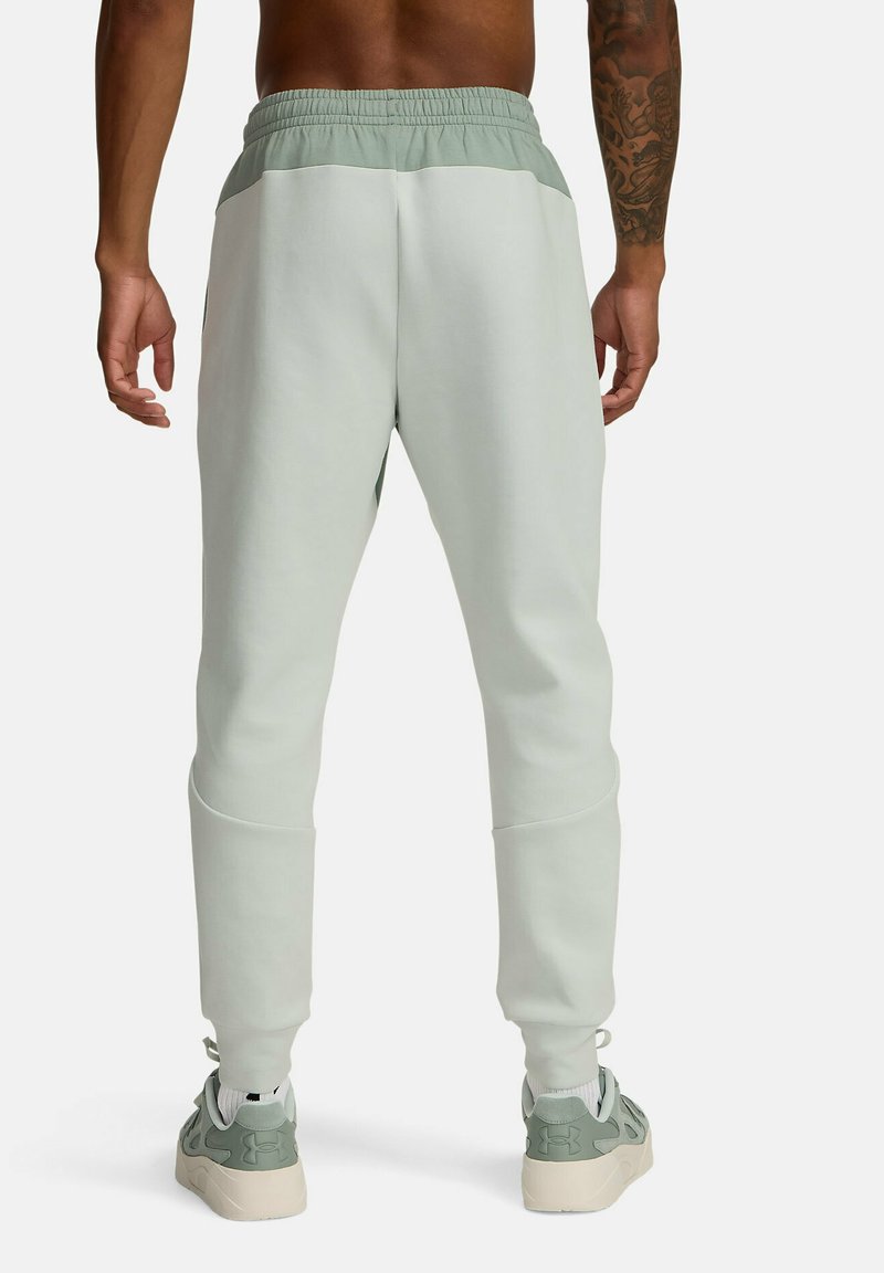 Joggers vert clair avec une taille élastique, coupe fuselée et panneau supérieur contrastant. Le matériau semble doux et légèrement texturé.