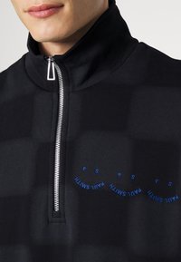 Pullover in pile nero con zip a un quarto e colletto alto. Presenta una zip argentata e un sottile testo ricamato blu "PAUL SMITH" sul petto.