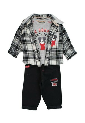 Chemise grise avec un motif de chien, veste en flanelle à carreaux noir et blanc, et pantalon en denim foncé avec des accents brodés et des poignets repliés.