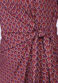 Baumwollstoff mit einem welligen Muster in Dunkellila, Pink und Grün. Merkmale eines gebundenen Knotendetails, mit glatter Textur und lebendigen Farben.