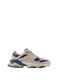 Zapatillas deportivas en tonos morado y gris, fabricadas con materiales de ante y malla. Presentan un logo amarillo con la letra "N", una suela intermedia gruesa y un acento en verde azulado.