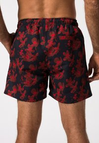 Pantaloni da mare neri con un motivo floreale rosso, vita elastica e tasca posteriore. Tessuto leggero e liscio con una vestibilità comoda.