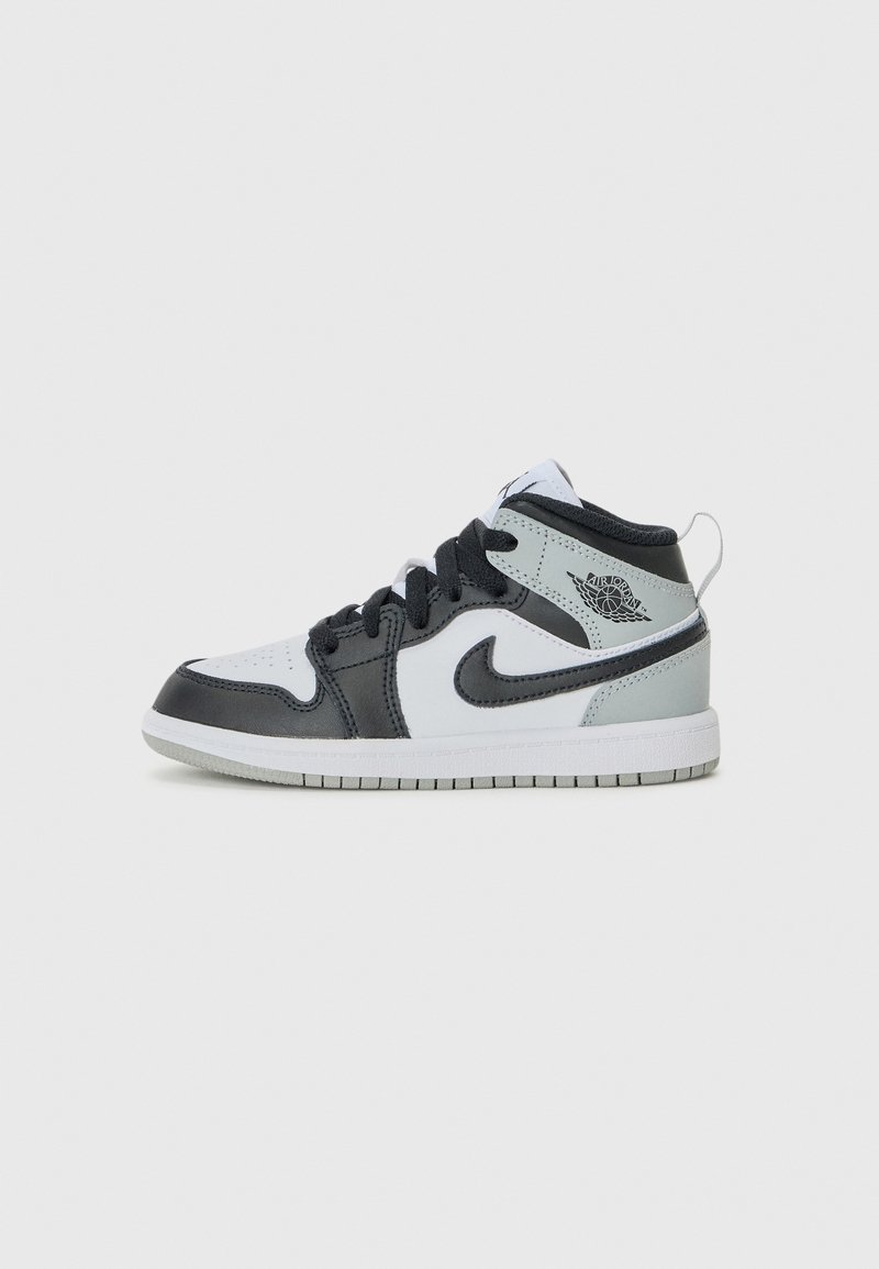 Baskets montantes Nike Air Jordan en noir, blanc et gris avec des lacets noirs et des accents sur la semelle, vues de profil sur fond blanc.