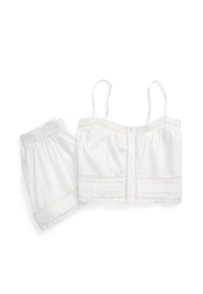 White cotton pajama set with thin straps, buttoned front top, elastic waist shorts, and lace trim details.