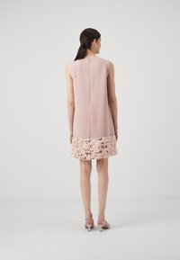 Vestido rosa sem mangas com um detalhe de lantejoulas texturizadas na bainha. Tecido suave, detalhe de fecho nas costas e corte até ao joelho.
