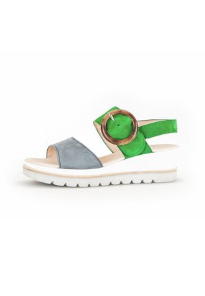 Multicolored sandal featuring a gray suede toe strap, bright green heel strap, large round wooden accent, and a white flexible sole.