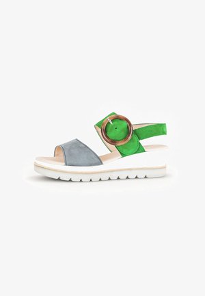 Multicolored sandal featuring a gray suede toe strap, bright green heel strap, large round wooden accent, and a white flexible sole.