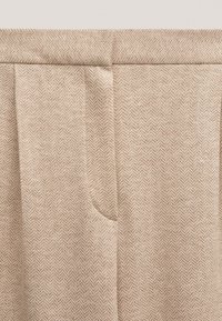 Beżowe spodnie w wzór rybiej ości, z pasem w talii i bocznymi kieszeniami, wykonane z teksturowanej tkaniny.